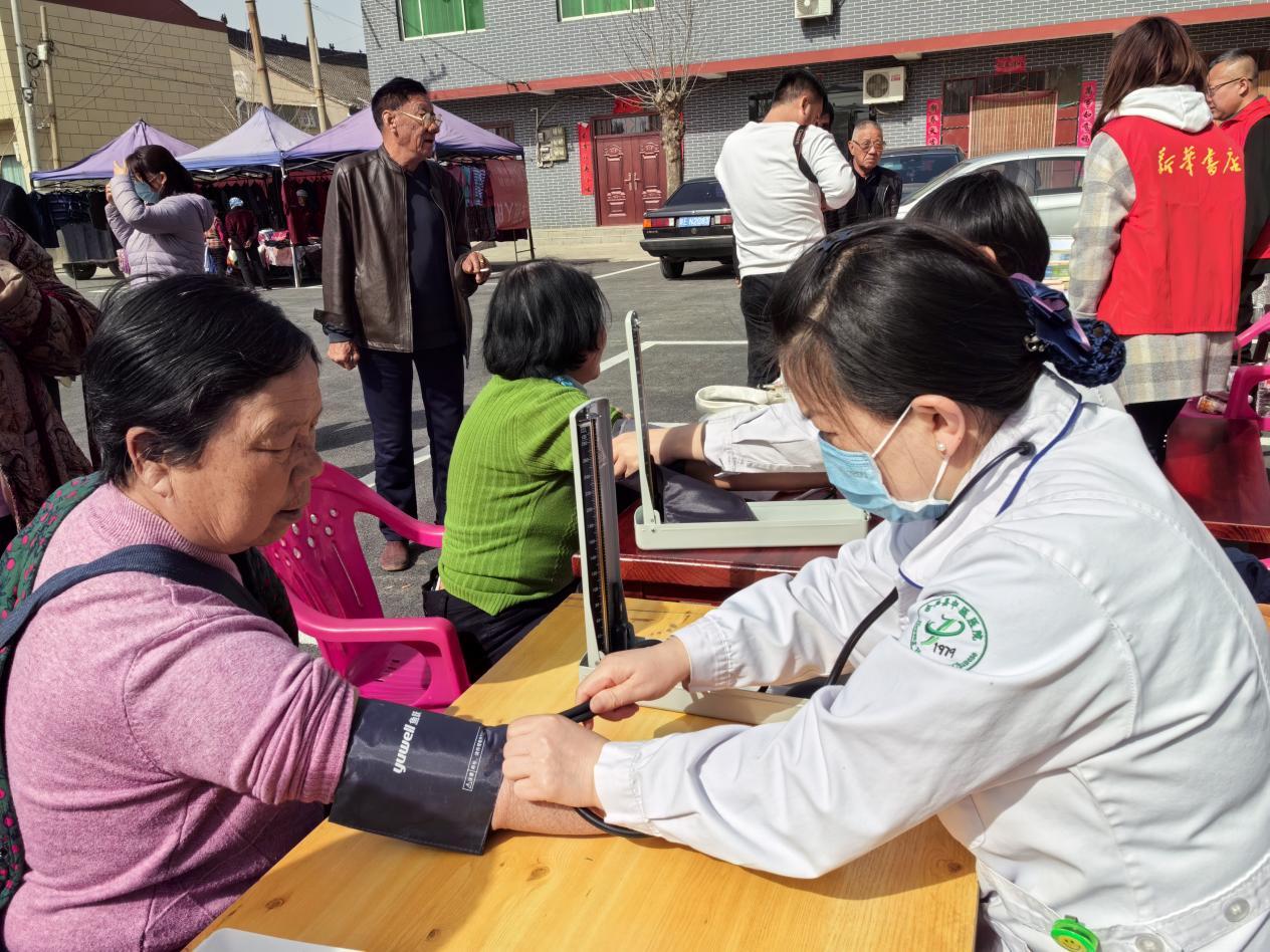 在医疗服务摊位前，医务志愿者为群众测量血压（本文图片由合阳县新池镇人民政府提供）