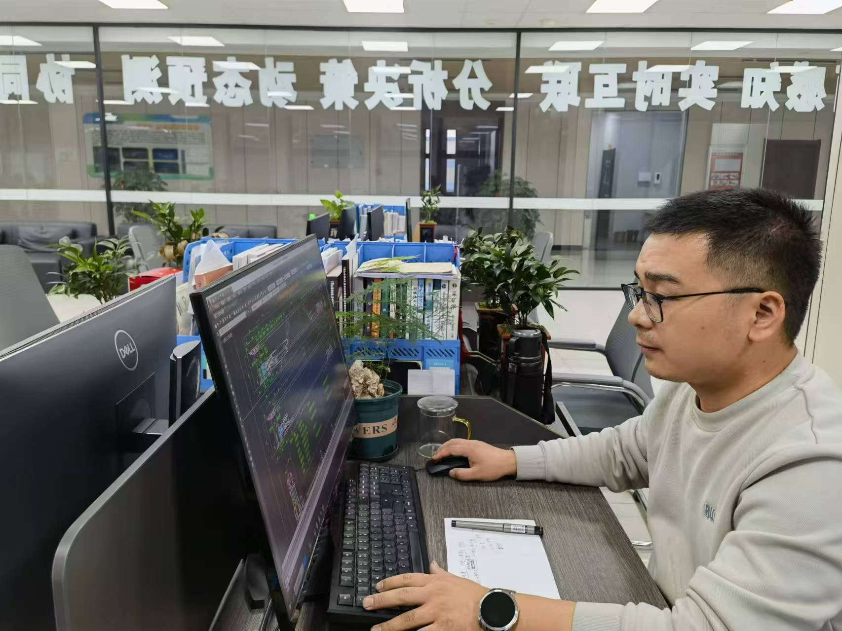 陈新在办公室查看采煤工作面设备配套图